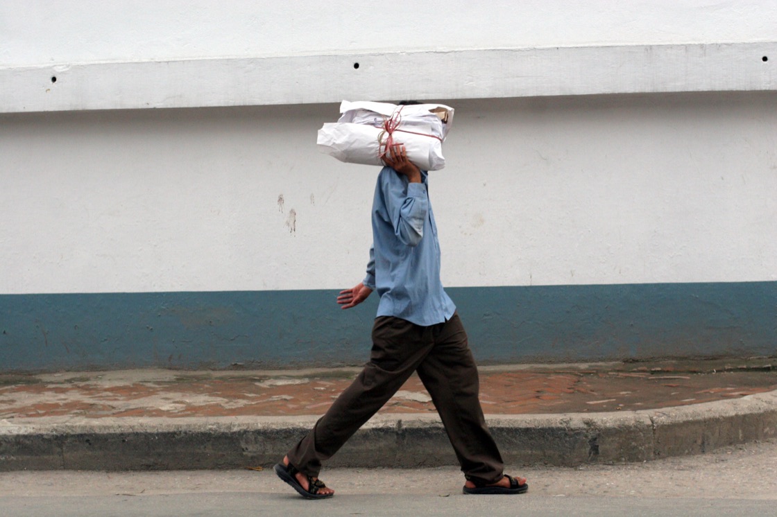 Copies of The Bhutan Reporter carried on a shoulder through a Nepali street